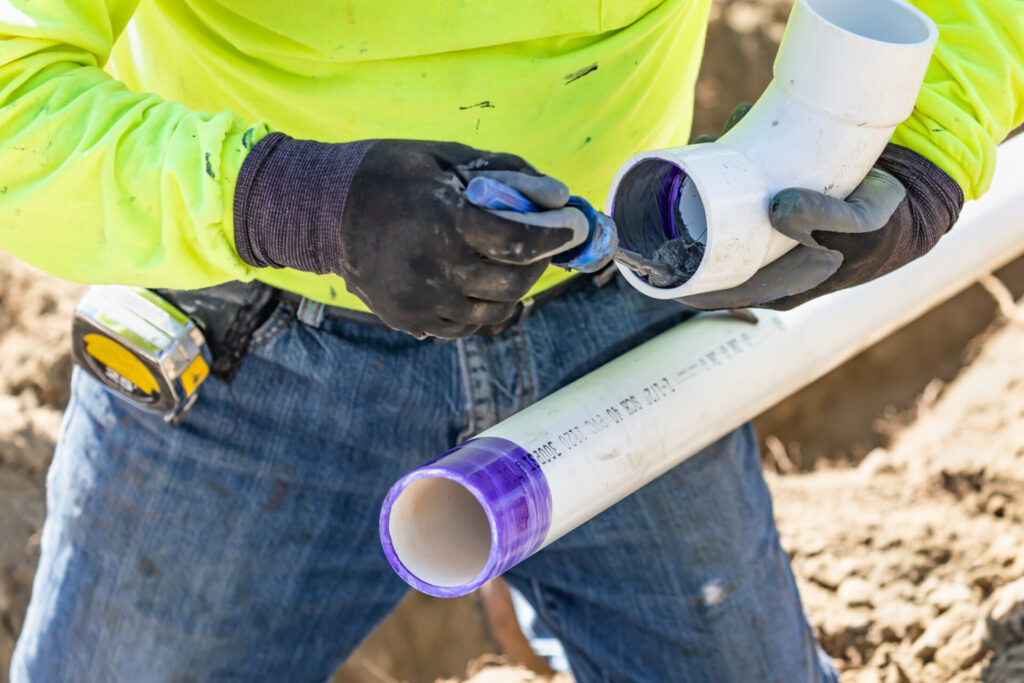 Plumber,Applying,Pipe,Cleaner,,Primer,And,Glue,To,Pvc,Pipe