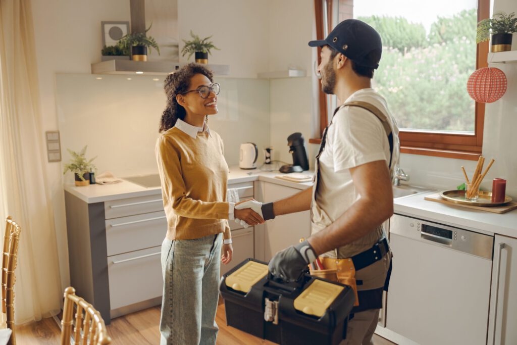 Professional,Repairman,In,Uniform,Shaking,Hands,With,Woman,While,Standing